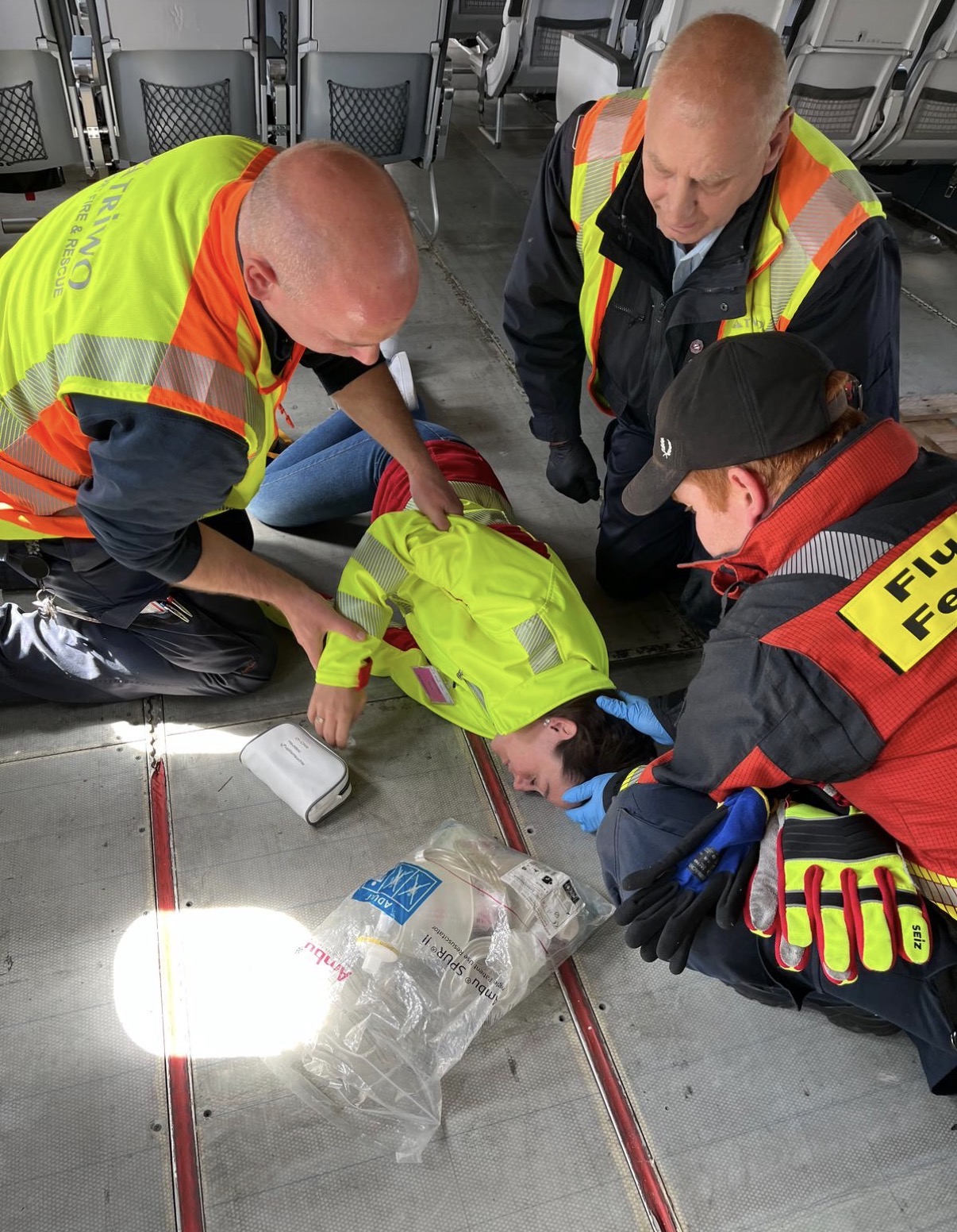 Praxisübung im Flugzeug: Einsatzkräfte versorgen eine am Boden liegende Person